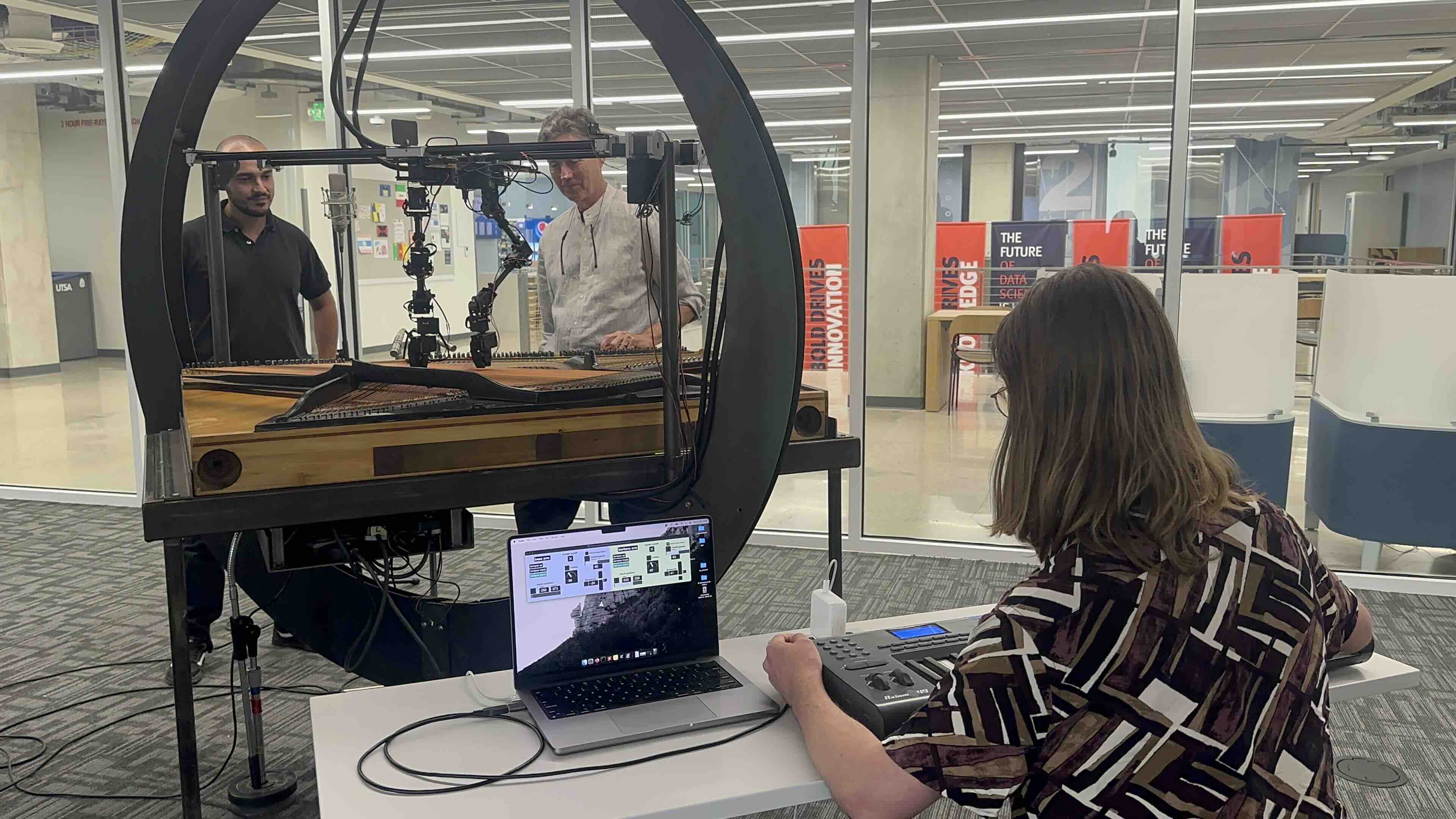 One person on a computer while two other people in front of Roz
