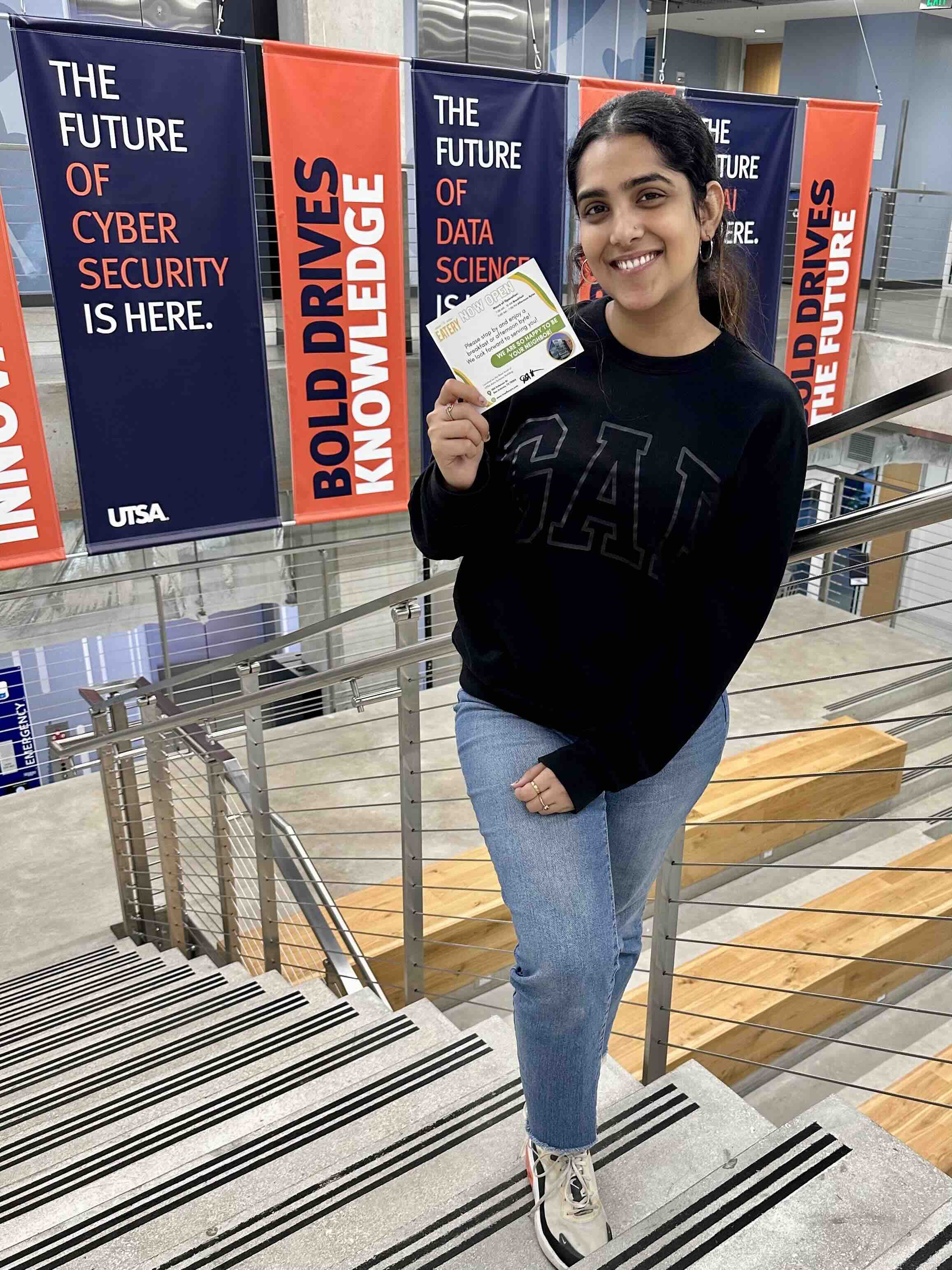 Fnu Ruchika at the top of stairs smiling holding a certificate